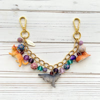 Cat bag charm with cat charms and a mix of purple and green beads on a gold chain. Cute bag chains for handbags. Purple bag cham.