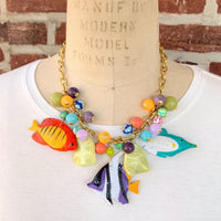 Tropical fish necklace for women. Colorful necklace for vacation outfit with tropical fish charms and assorted bright colored round beads on a gold chain.