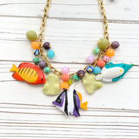 Tropical fish necklace for women. Colorful necklace for vacation outfit with tropical fish charms and assorted bright colored round beads on a gold chain.