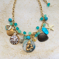 Mermaid charm necklace for vacation outfit ideas. Aqua blue beads, seashells, starfish, anchor charm and mermaid pendant necklace for summer.