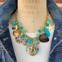Mermaid charm necklace for vacation outfit ideas. Aqua blue beads, seashells, starfish, anchor charm and mermaid pendant necklace for summer.