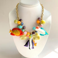 Tropical fish necklace for women. Colorful necklace for vacation outfit with tropical fish charms and assorted bright colored round beads on a gold chain.