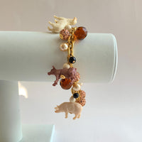 Gold chain charm bracelet with farm animal charms, pearls, peach rhinestone beads and brown faceted beads.