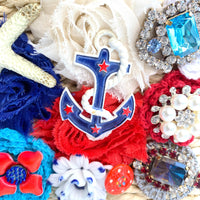 Nautical tote bag detailed with red, white and blue frayed edge fabric rosettes, star fish, anchor, blue rhinestone, and vintage buttons. Light beige woven handbag with drawstring fabric inner lining and top handle. Straw summer handbag.