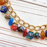 Assorted color and shaped floral glass millefiori glass beads dangling from a gold purse bag chain. Floral lampwork beads on a gold chain. Lenora Dame bag chain.