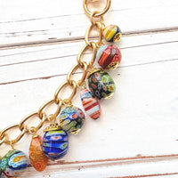 Assorted color and shaped floral glass millefiori glass beads dangling from a gold purse bag chain. Floral lampwork beads on a gold chain. Lenora Dame bag chain.