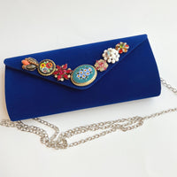 Royal blue velvet clutch purse detailed with seven vintage pearl and rhinestone earrings and miniature mosaic brooches and a silver chain removable strap.