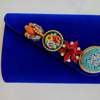 Royal blue velvet clutch purse detailed with seven vintage pearl and rhinestone earrings and miniature mosaic brooches.