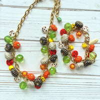 Lenora Dame necklace and bracelet with a gold chain filled with orange and white jack o lantern beads, orange pumpkins, yellow sugar skull beads, black pumpkins, and green beads. Cute jewelry for fall.
