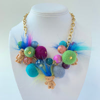 Troll dolls necklace with miniature trolls dolls with crazy hair and a mix of felt balls and beads on a gold chain.