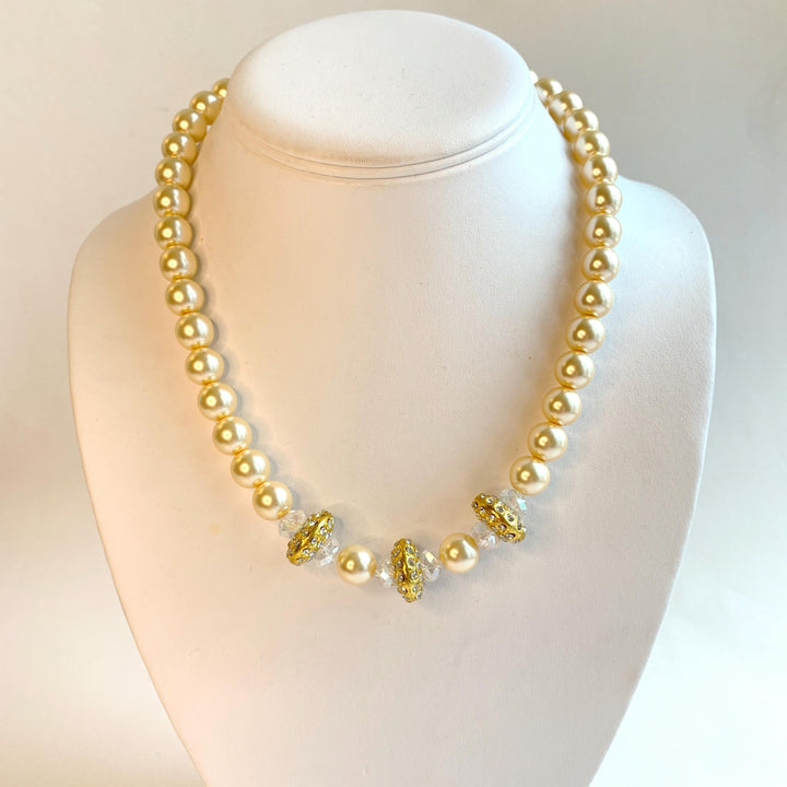 Cream pearl choker necklace for women with gold spacers embedded with rhinestones in the center. Modern traditional bridal jewellery.