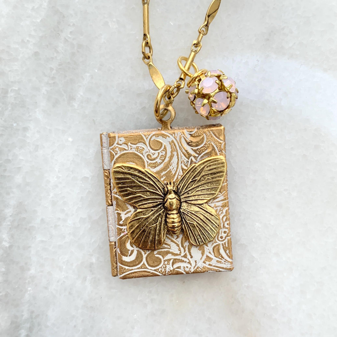 Gold locket necklace with brass butterfly metal stamping detail hung on a gold chain. Locket necklace for women.