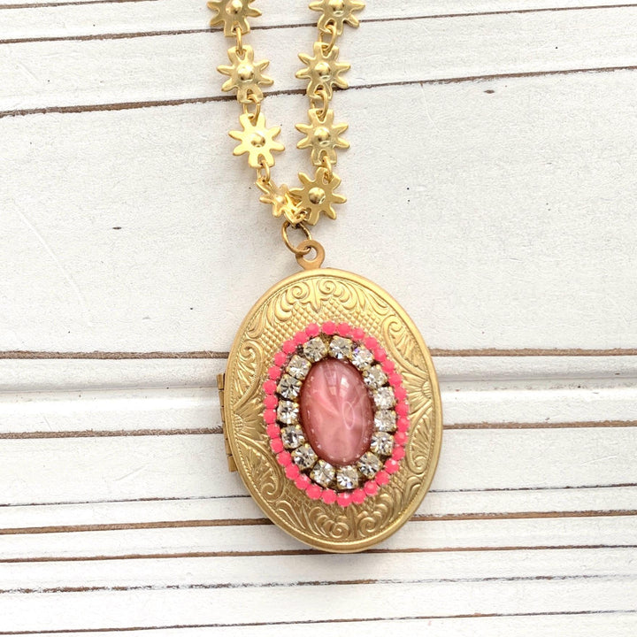 Gold oval locket necklace. Locket necklaces for women. Gold textured oval locket embellished with pink and crystal rhinestones hanging on gold daisy chain. 