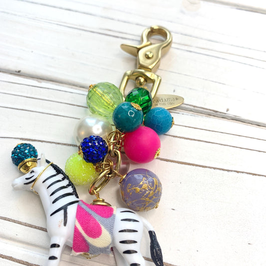 Beaded bag charm with assorted colorful beads wire wrapped on a brass plated chain with embellished zebra figurine at the bottom.