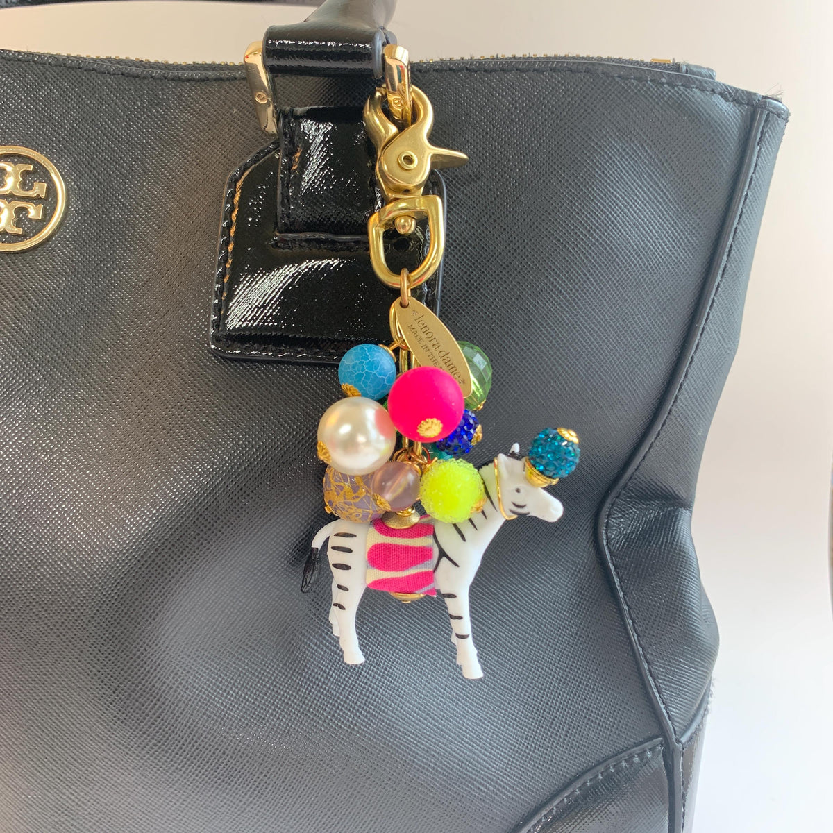 Colorful cute bag charm on a black handbag. Lenora Dame bag charms.