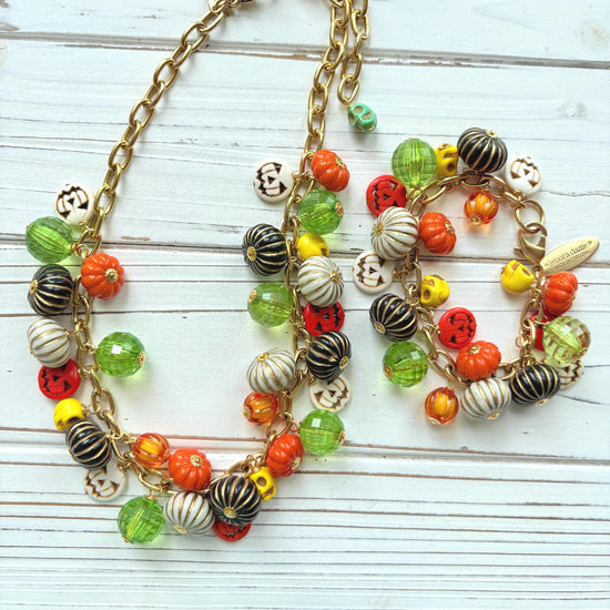 Lenora Dame necklace and bracelet with a gold chain filled with orange and white jack o lantern beads, orange pumpkins, yellow sugar skull beads, black pumpkins, and green beads. Cute jewelry for fall.