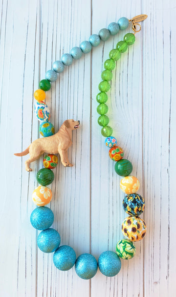 Long beaded Labrador Retriever necklace. Beaded necklace with toy yellow Labrador Retriever strung with blue beads, green beads, yellow beads and sunflower beads.